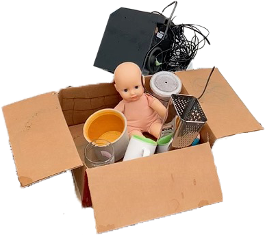 Photo of a box of garbage incluing a baby doll and a cheese grater